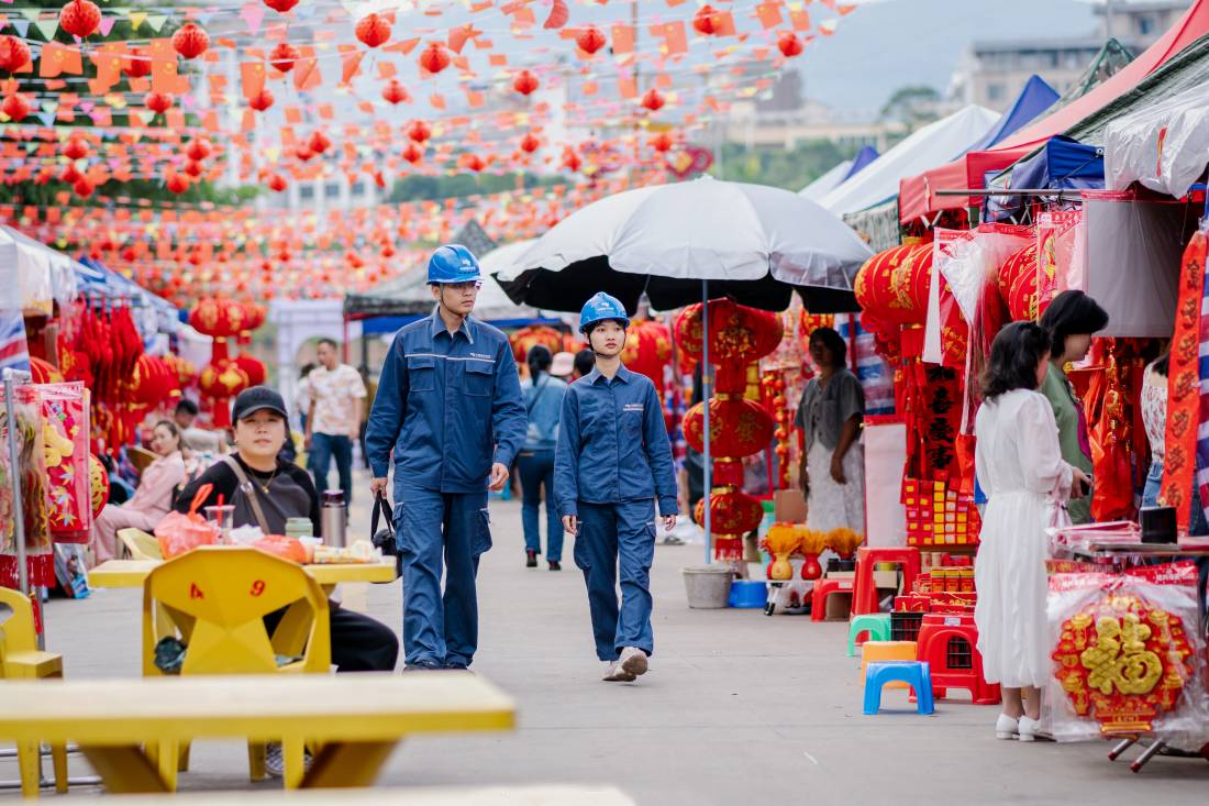 2月4日,海南省白沙黎族自治县牙叉河边上开启年货市场模式,南方电网保供电人员到现场进行用电检查,为用户讲解安全用电注意事项。(余盛本 摄).jpg