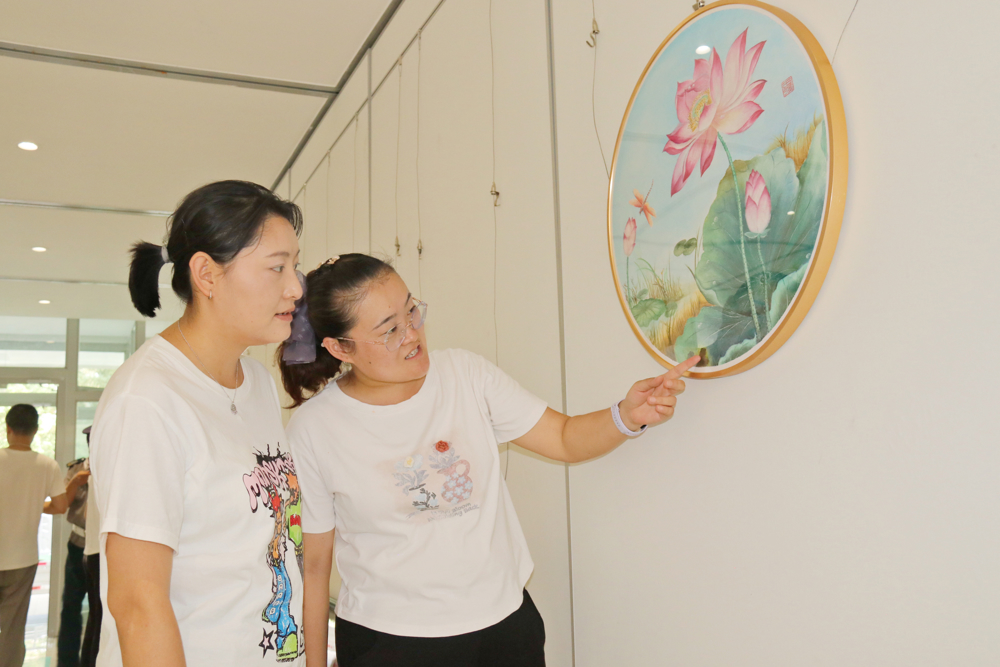 图二、大家在师市“丹青润廉心 光影传正气”廉政书画摄影展出的作品前热切交流，在笔墨光影之间感悟廉洁文化。（夏艳琦摄）