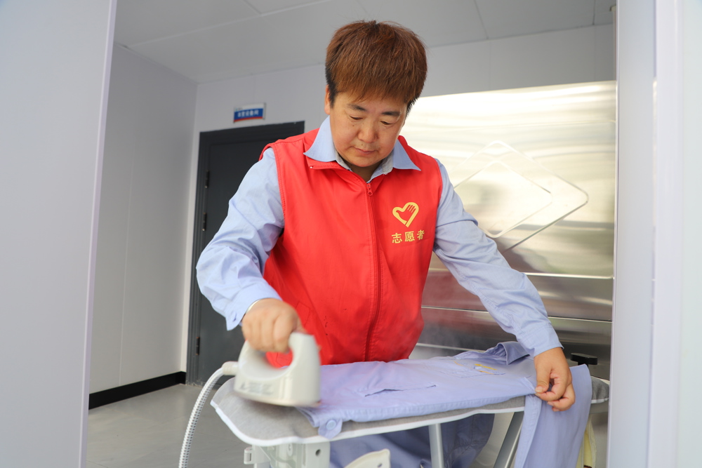 “暖心”志愿者对清洗完毕的职工工装进行熨烫整理，保障一线职工着装整洁平整。