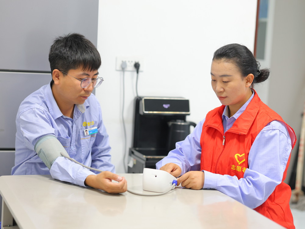 图为天辰化工厂高盐废水车间志愿者正在为职工臧桥年测量血压和心率。（宋武 摄）