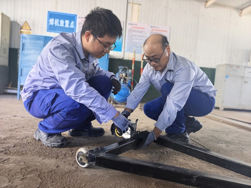 图三：天伟化工厂机修车间巧用钢管、手拉葫芦等废旧材料，自主研制便携式起重搬运小车。（王健蓉摄）