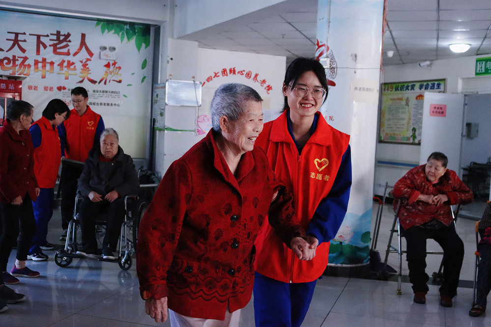 图为：志愿者搀扶老人